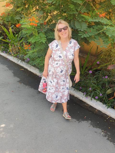       Woman in floral dress near plants.
  
