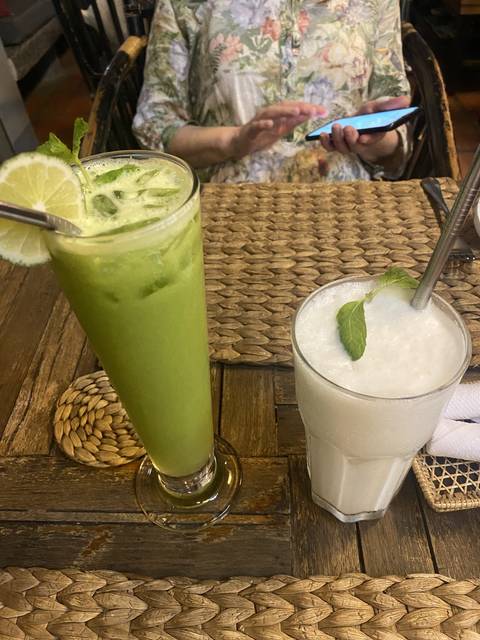 Two drinks on a table with partially visible person.