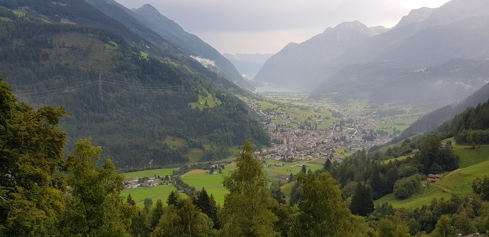 Panoramic view of a valley with mountains and a lake.