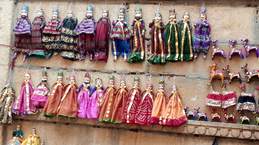 Colorful traditional dolls displayed on a wall.