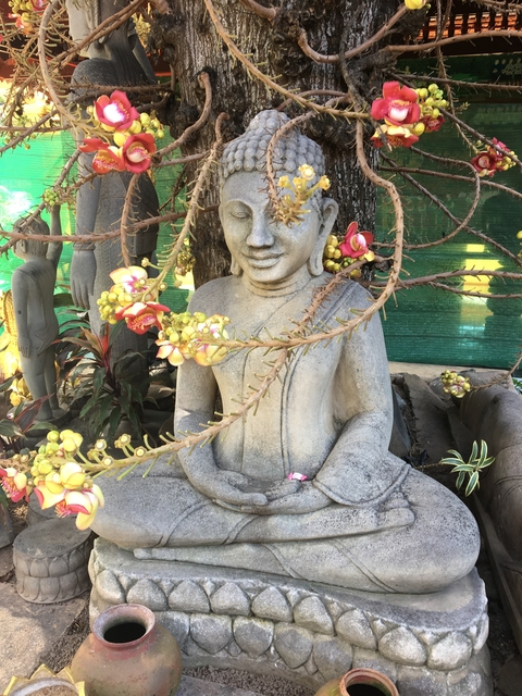 A Buddha statue surrounded by flowers and greenery.
