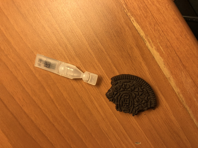A half-eaten cookie and a small test tube on a wooden surface.