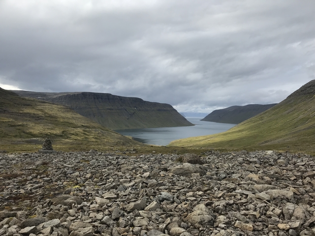 Majestic fjord landscape with rocky ground and cloudy sky.