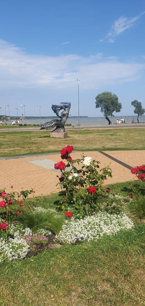 A flower garden with a sculpture along a pathway.