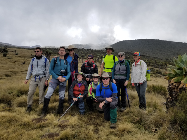 A group of hikers posing on a trail under cloudy sky.