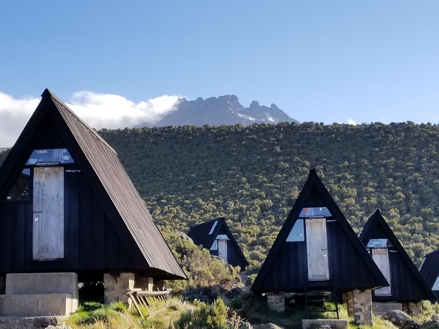 A series of mountain huts with a peak in the background.
