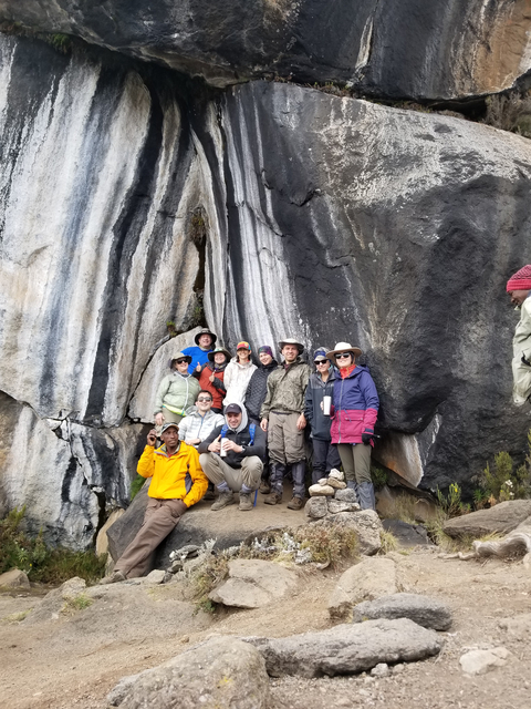 A group of hikers posing in front of a rock formation.