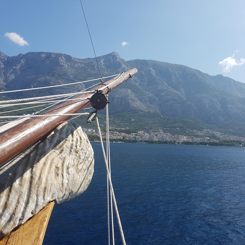       View from a ship with ropes and cityscape against rocky mountains.
  