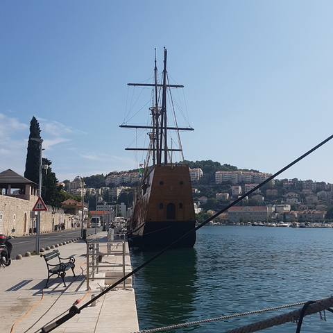 Large ship docked at a harbor with backdrop of buildings.