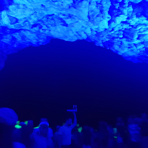 Blue-lit cave interior with faint view of structure.