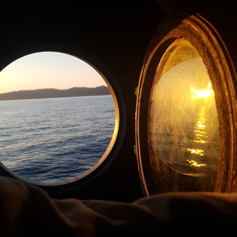 Sunset through porthole with view of the sea.