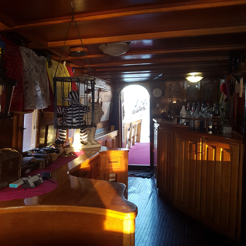       Interior of a wooden ship cabin with a bar and decorative elements.
  
