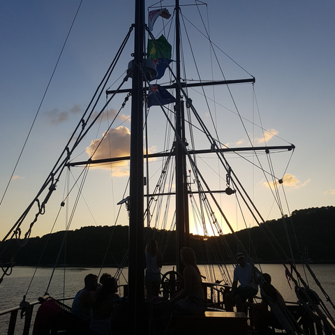       Silhouette of ship masts against sunset.
  