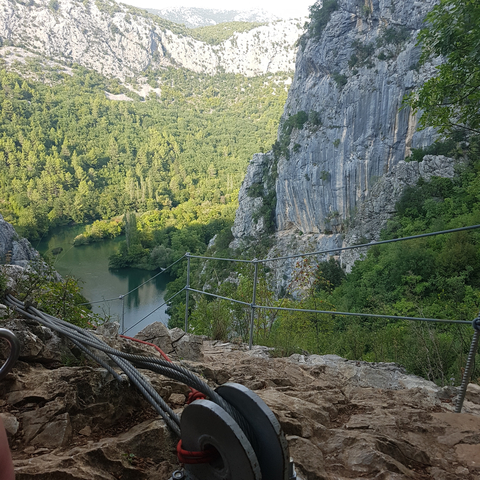       Hiking trail with rocky cliffs and green river below.
  