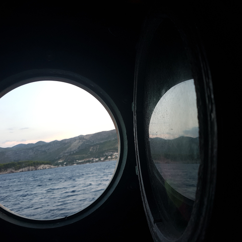       View through porthole of sea and coastline.
  