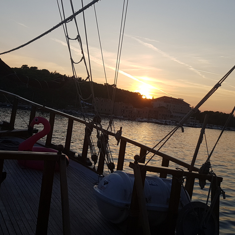Yacht at sunset with silhouetted landscape.