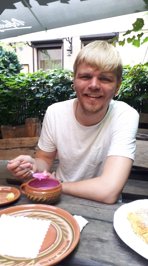 Man with a dish, smiling while sitting at a table.