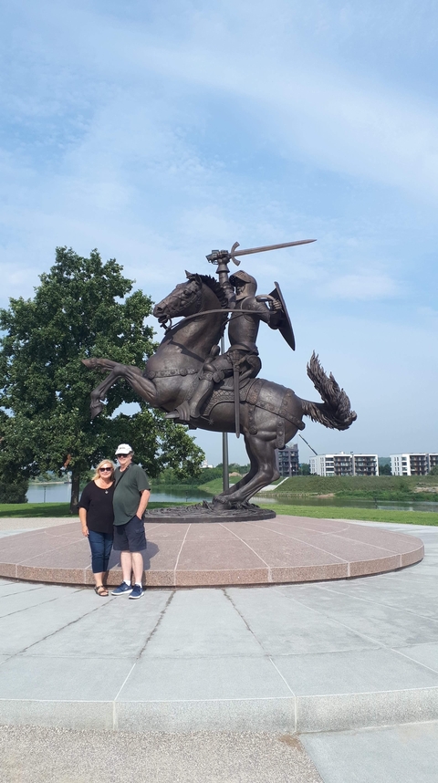 Two people smiling at the camera beside a horse statue.