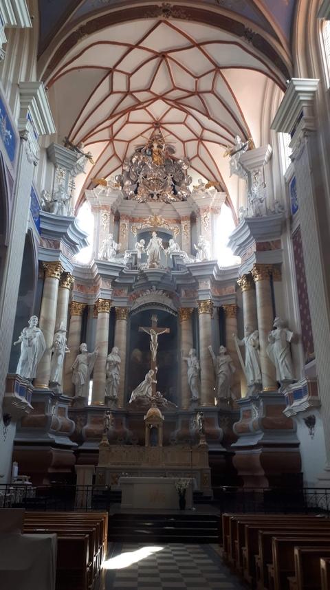 Inside of a decorated church with statues and chandeliers.