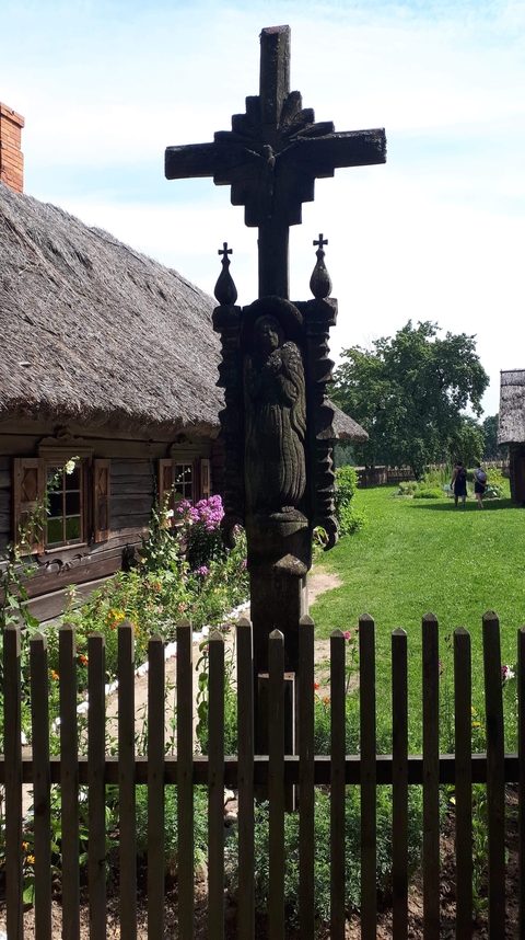 Traditional wooden houses surrounded by greenery and people walking.