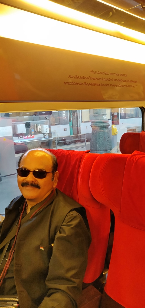 Person sitting inside a train with outdoor view through the window.