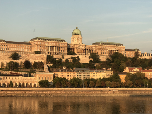 Grand building with a green dome along a riverfront.