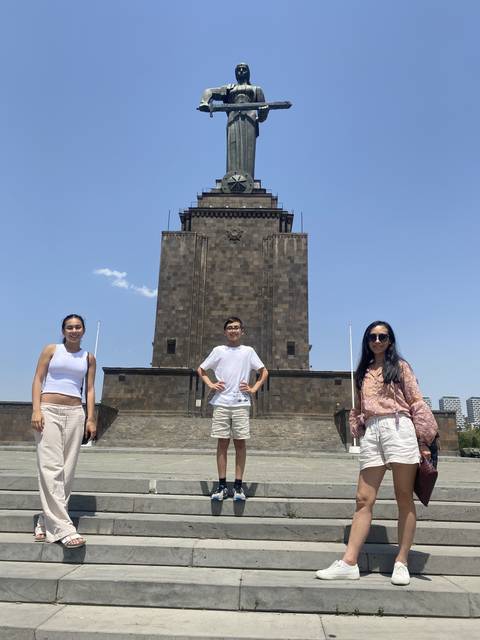       Three people posing in front of a monument.
  
