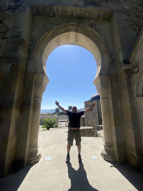       Man standing under an arched gate.
  