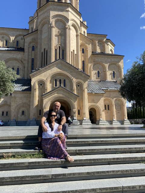       A couple sitting on steps in front of a large cathedral.
  