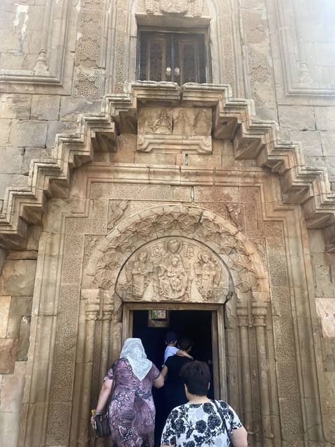       Group entering a historic stone building through an ornate door.
  