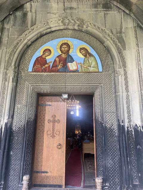       A person admiring artistic wall carvings at a church entrance.
  
