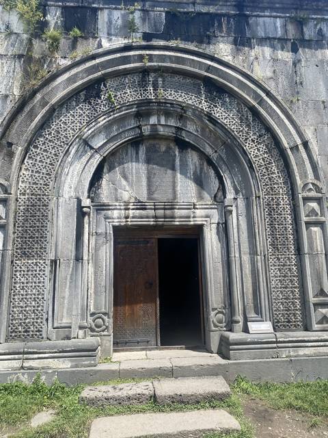       An ornate church entrance with a wooden door.
  