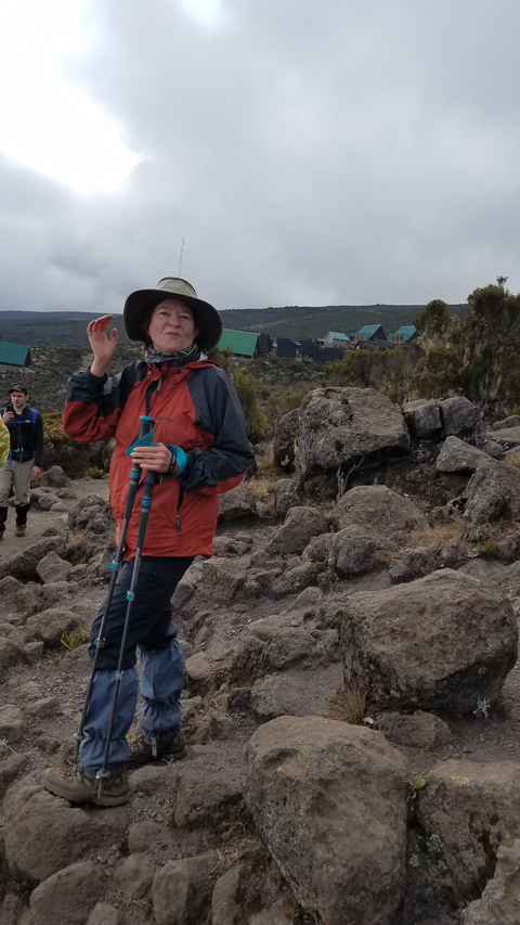 Woman holding trekking poles on a mountain trail.