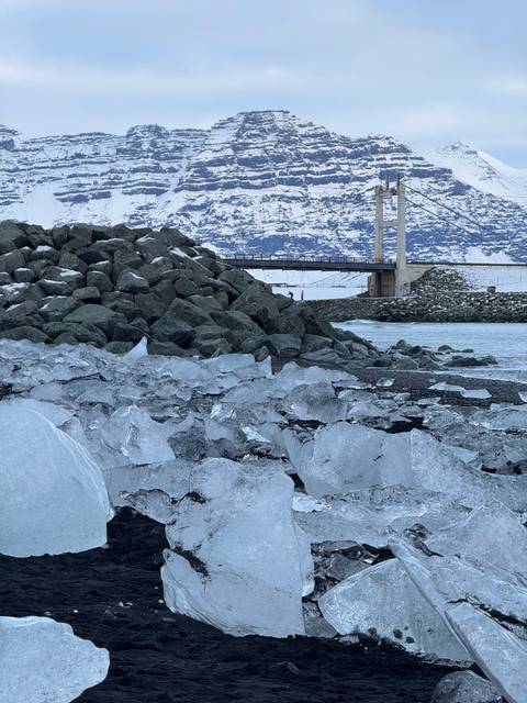 Icy landscape with visible snow and rocks by a water's edge.