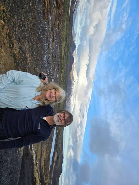 Couple posing in front of Icelandic landscape with snow-capped mountains.