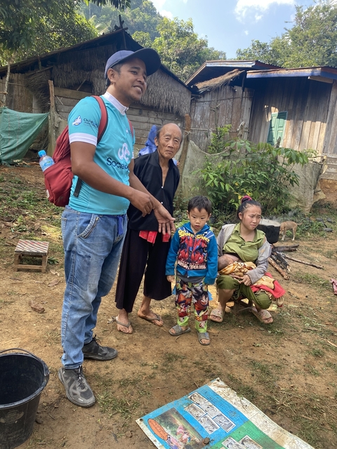       Group of people, including a child, in a rural setting with plants and a dog.
  
