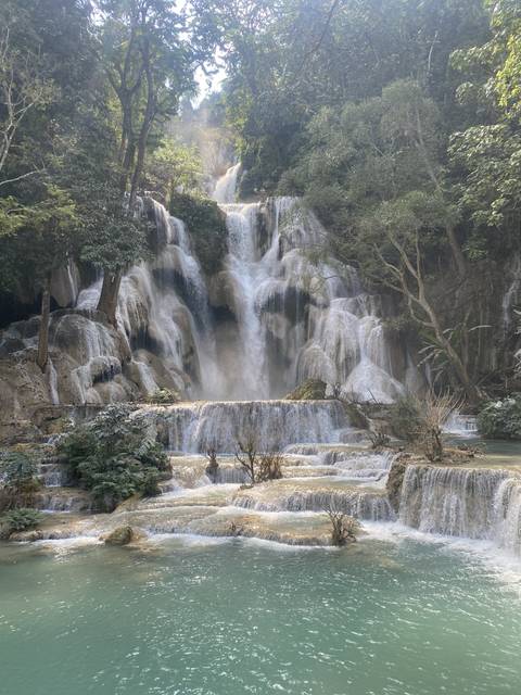       Waterfall cascading down rocky ledges surrounded by trees.
  