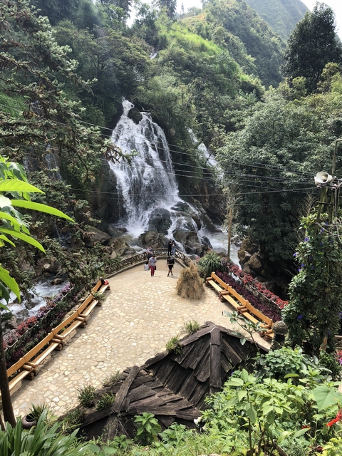 Waterfall with a bridge crossing and tourists admiring the view.