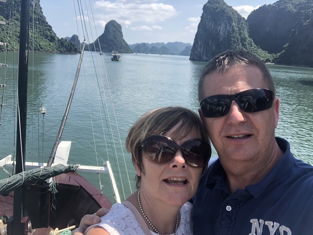 Tourists taking a selfie on a boat with limestone formations in view.