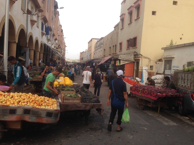       Street market scene with fruit and vegetable stalls.
  