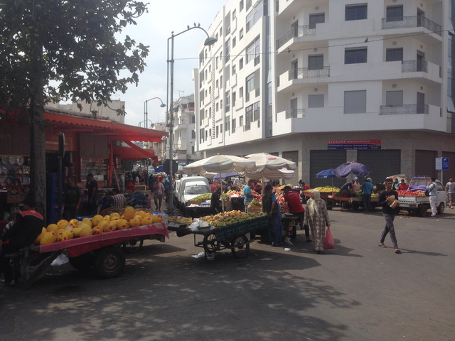 Busy open-air street market with various stalls and shoppers.