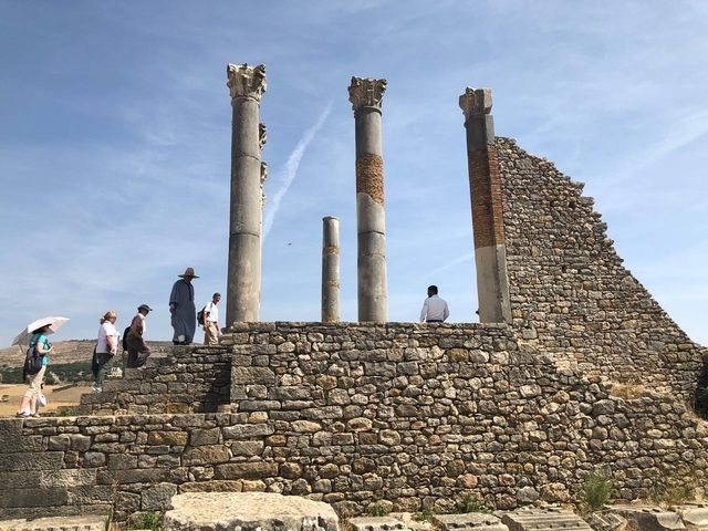 Ancient ruins with historic columns and tourists exploring.
