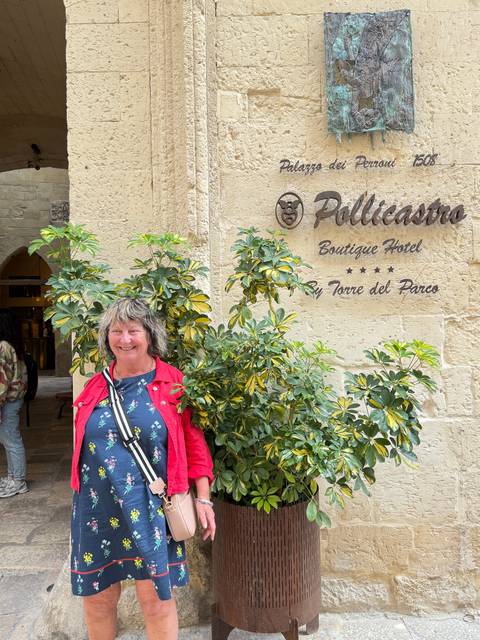 Woman posing by a stone wall with engraved text.