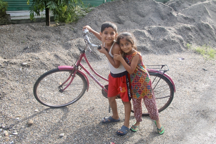 Two children posing with a bicycle.