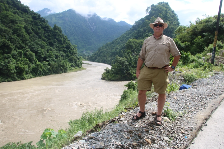       Man in a hat standing by a river.
  