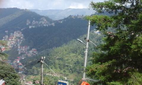 Hilly landscape with electricity poles and scattered buildings.