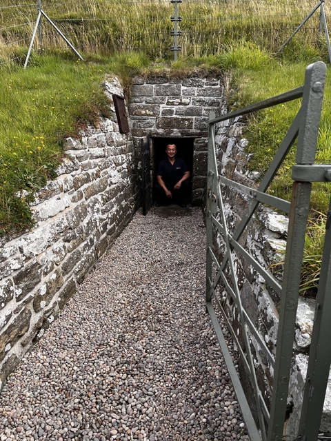 Person crouching in a small entrance of a stone structure.