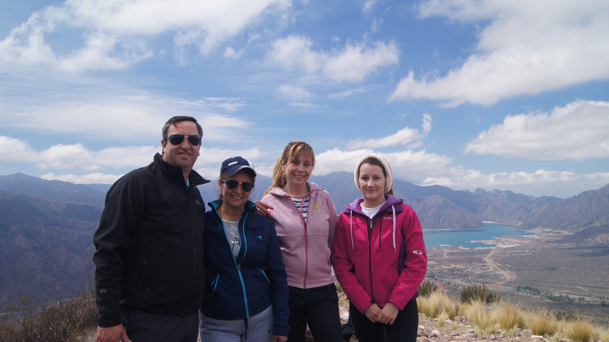       A group of people posing in front of a scenic mountain and lake view.
  
