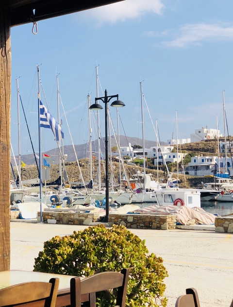 Port with yachts and boats, surrounded by hills and Greek houses.