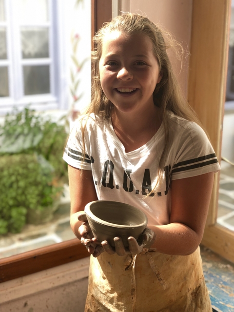 Woman indoors posing with a ceramic pot she made.